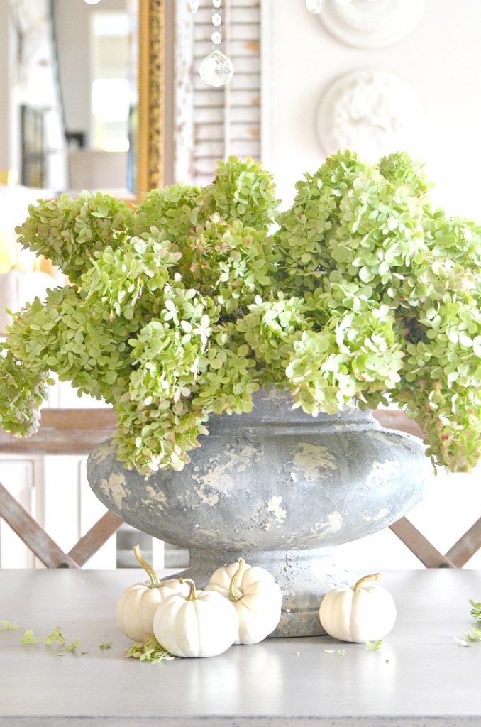 big urn centerpiece on the dining room table with green hydrangeas