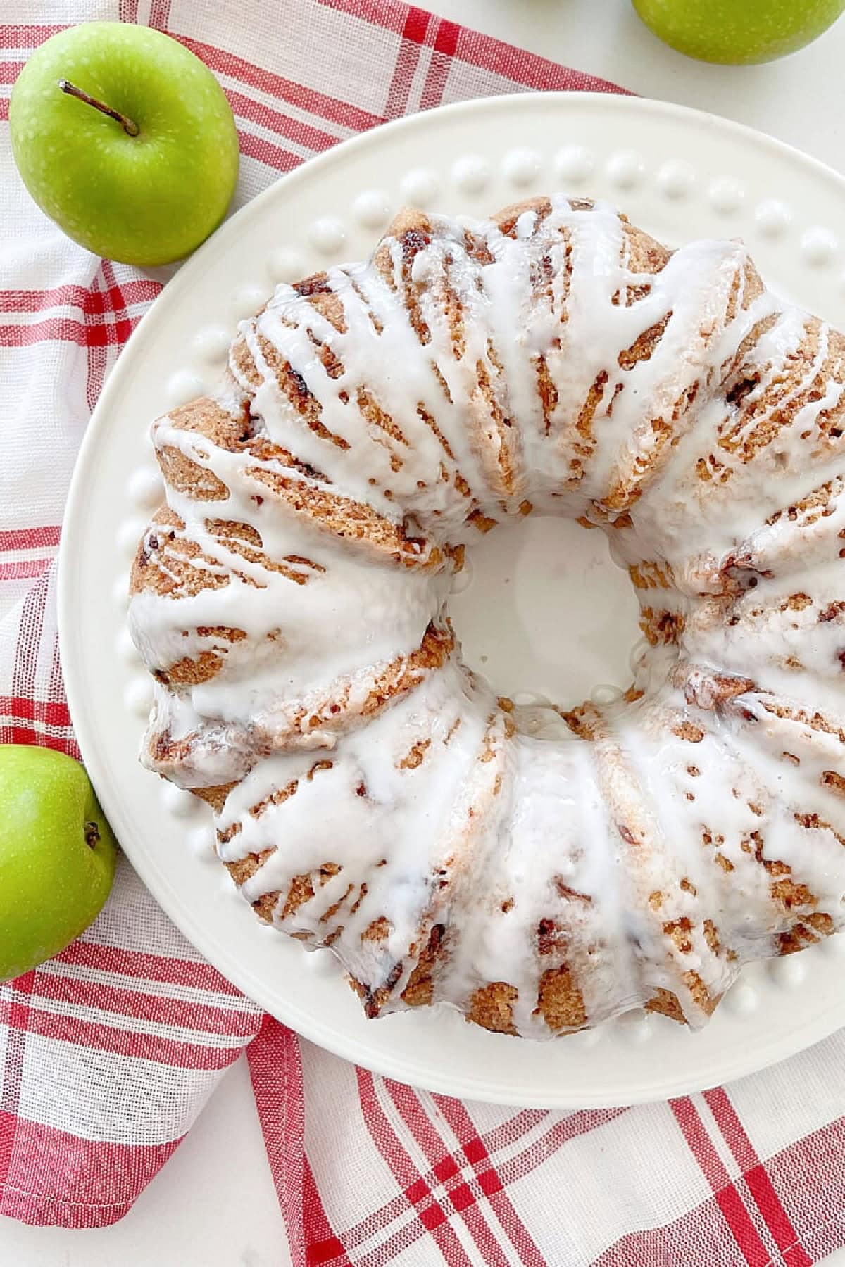 apple cake on a red and white dish towel with green apples