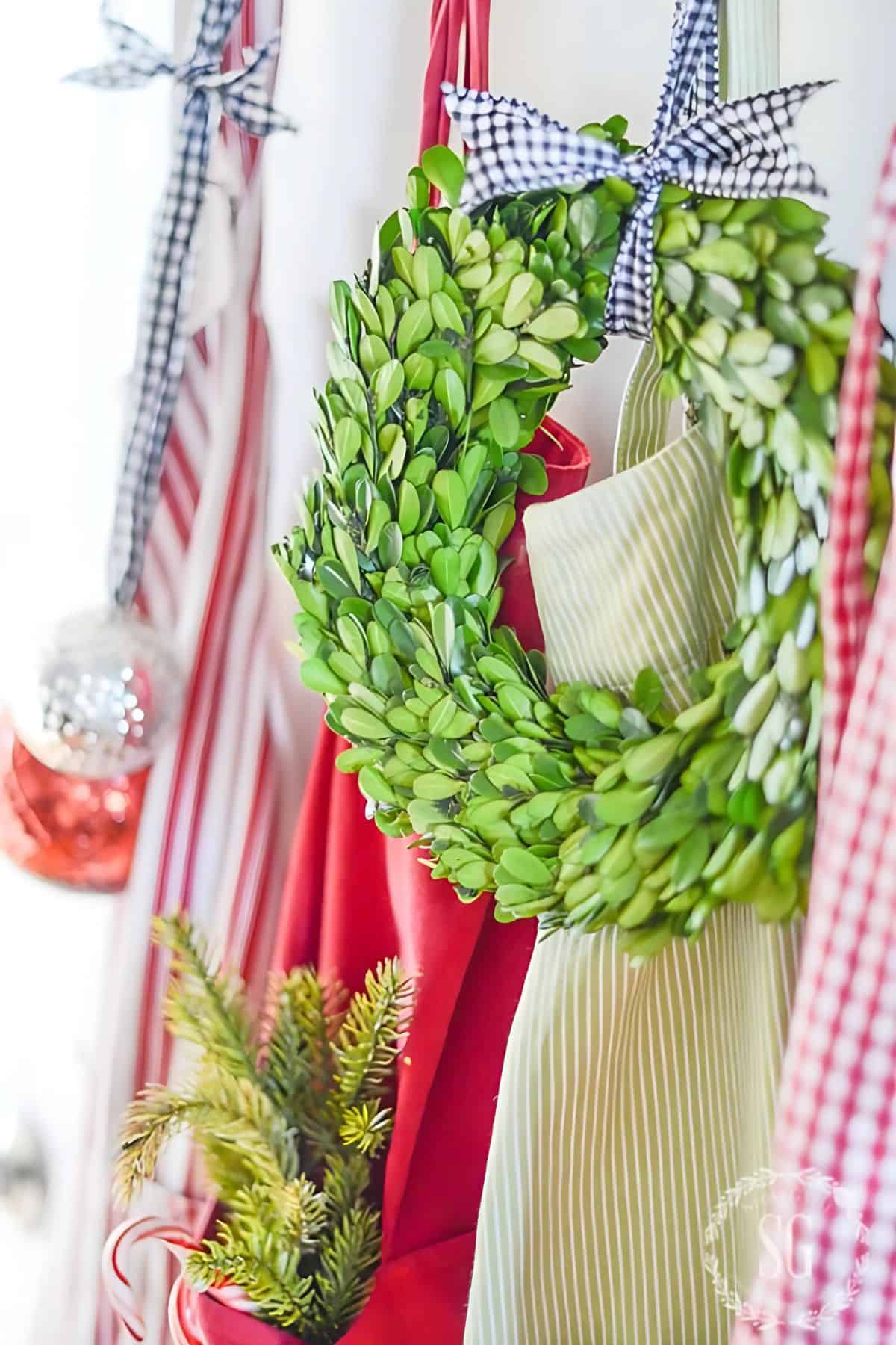 a small wreath hanging on a hook with aprons