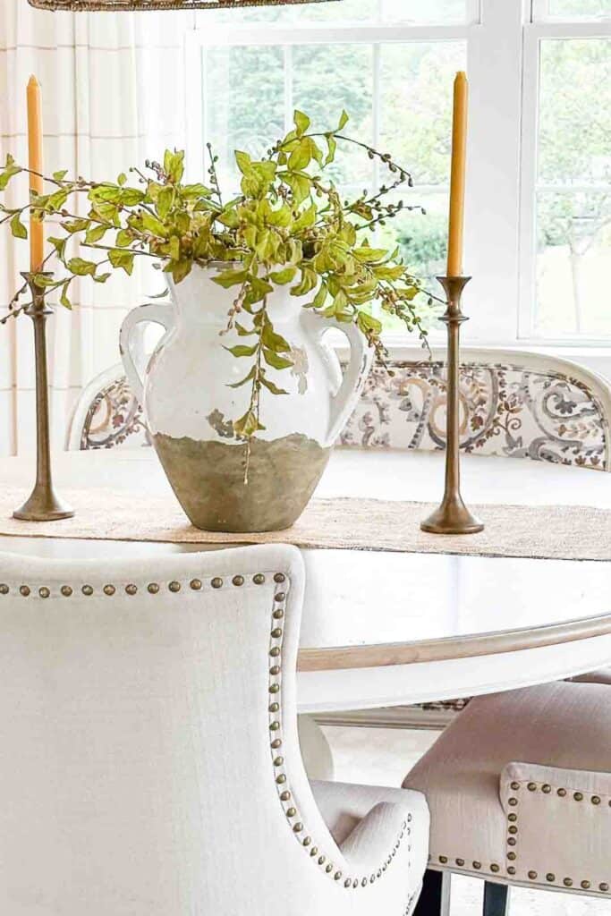 dining room table decorated with a large urn and greens
