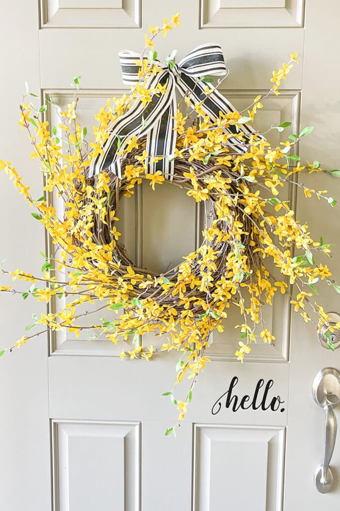 forsythia wreath on a door with a black and white ribbon