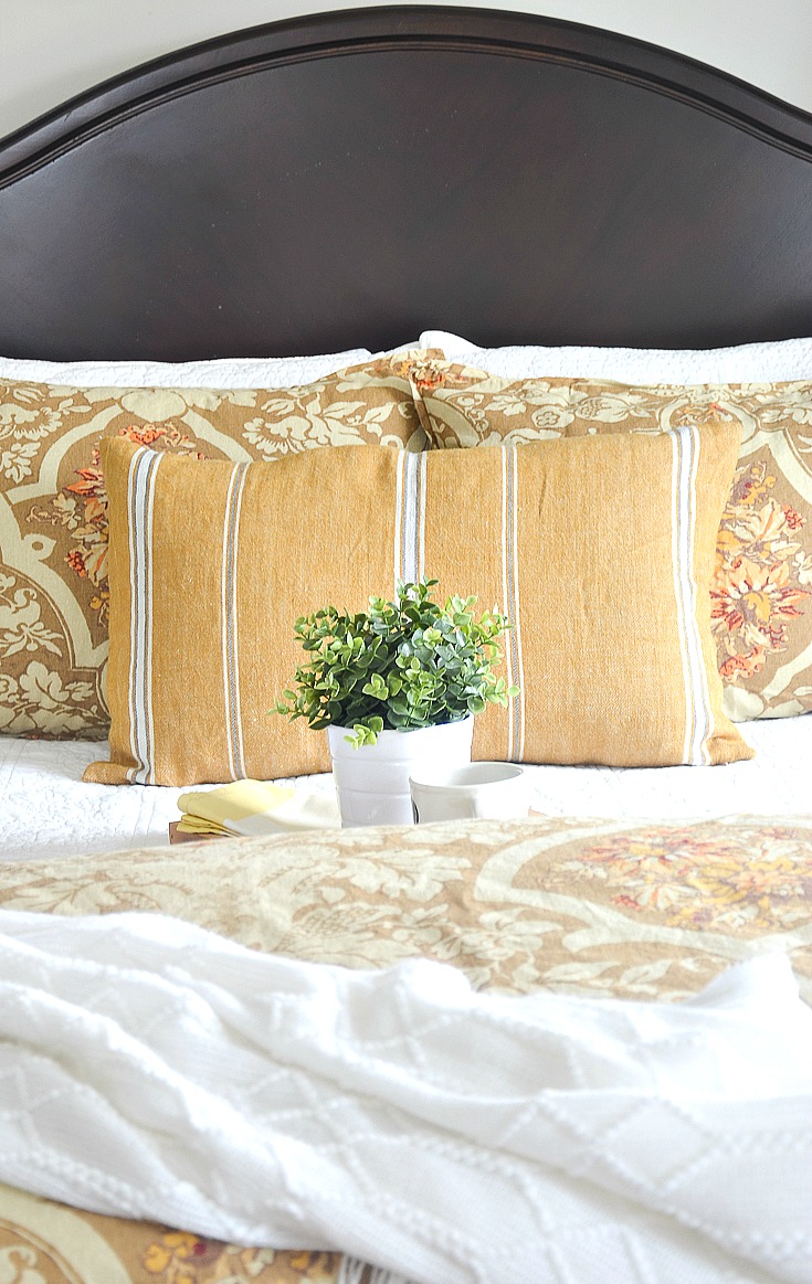 img src;"guest bedroom".png alt= "Gold quilt and pillows on bed in guest room">
