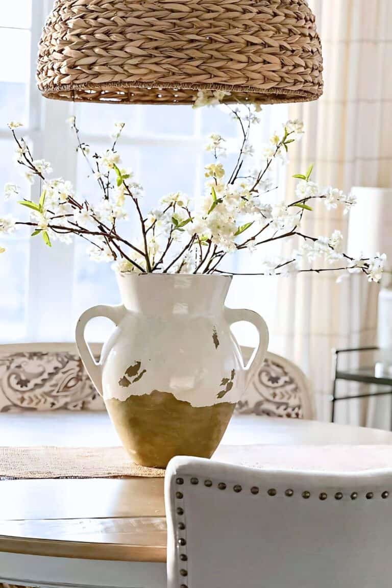 URN OF BLOOMING SPRING BRANCHES IN AN URN ON A DINING ROOM TABLE